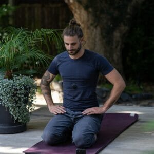 a man sitting on a man sitting on a yoga mat with his hands in his pockets